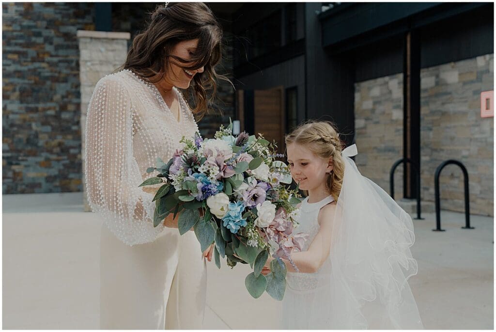 Bride with daughter letting her look at flowers