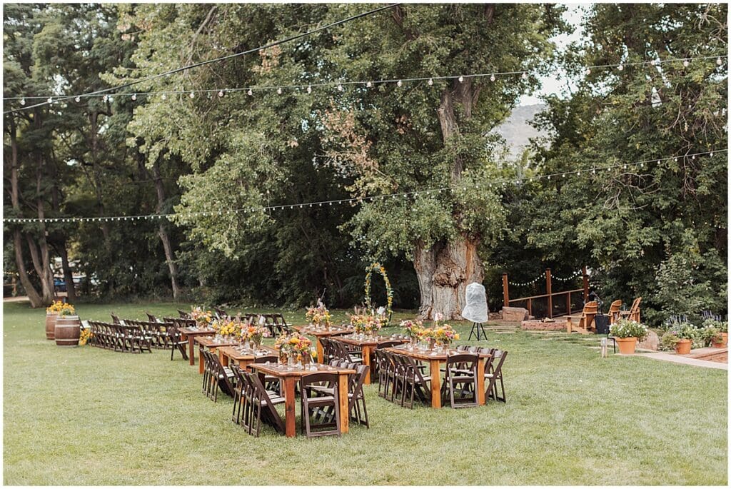 Farm tables set up on the lawn under string lights